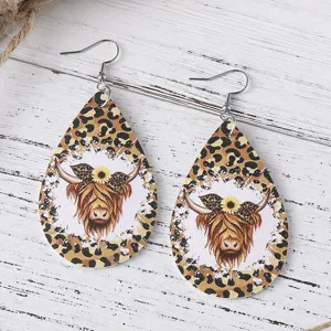 Detailed closeup of teardrop faux leather earrings featuring highland cow sunflower leopard.