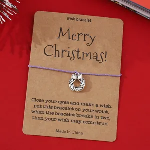 Nahaufnahme Detail des Weihnachtswunscharmbands mit Metallkranzanhänger auf Kraftpapierkarte.