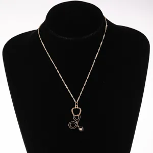 Close-up detail of the gold stethoscope pendant necklace with stylish black enamel.