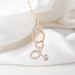 Gold-plated stethoscope pendant necklace with white enamel detail, elegant medical theme jewelry.