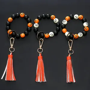 Halloween beaded wristlet keychain with wooden beads, pumpkin face design, leather tassel.