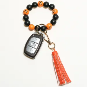 Halloween wooden bead wristlet keychain detail showing black orange pumpkin charms and leather tassel.