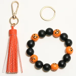 Close up detail of Halloween wooden bead keychain with orange leather tassel and pumpkin face.