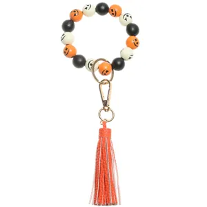 Close-up detail of Halloween wooden bead wristlet keychain with vibrant orange leather tassel.