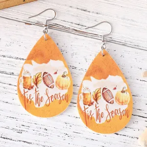 Gros plan de boucles d'oreilles en cuir en forme de goutte d'automne avec des citrouilles.