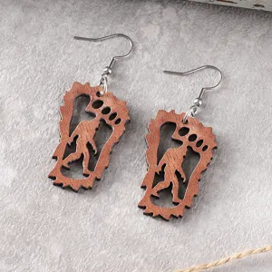 Detaillierte Nahaufnahme von hölzernen Bigfoot Ausschnitt baumelnden Ohrringen aus Metall.