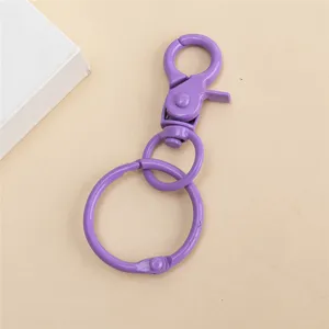 Detalle de llavero de metal morado, mosquetero pintado de colores y anillo para manualidades.