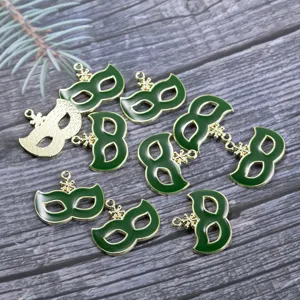 Detailed close-up of green masquerade mask alloy charms with snowflake rings for DIY jewelry.