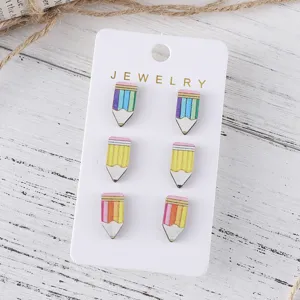 Close up view of cute pencil shaped wooden stud earrings detail display card rustic wood background.