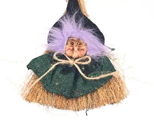 Primer plano de la decoración colgante de bruja de Halloween con escoba, pelo morado y atuendo.