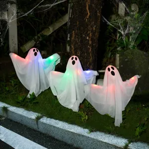 Outdoor Halloween glowing ghost decorations scene with LED lights on grass at night.
