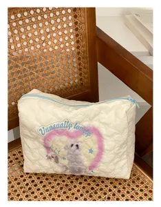 Detailed view of the quilted cosmetic bag with cute puppy print and heart pattern design.