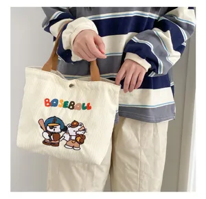 Corduroy tote bag with cute baseball cartoon embroidery and brown handles for daily use.