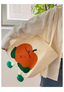 Detailansicht der Leinentasche mit niedlichem orangefarbenen Apfel-Print und Plüschbeinen.