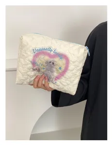 Quilted cosmetic pouch detail view, off-white makeup storage bag with cute puppy heart print and blue zipper.