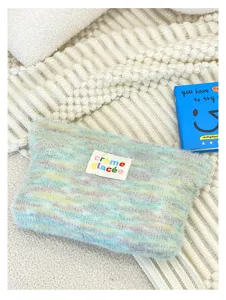Knitted plush cosmetic bag detail, soft fuzzy texture with colorful knit design and label.