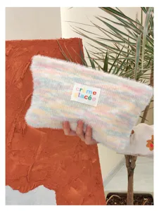Detailed shot of the colorful plush knit cosmetic pouch, soft texture with cute label.