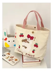 Cute corduroy handbag with sweet embroidered rabbit and cherry design, pink handles, detail view.