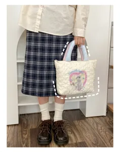 Gesteppte Handtasche mit plüschigen Griffen und niedlichem Hündchen Motiv Detail.