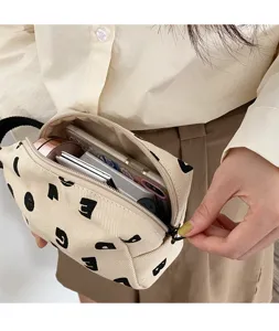 Vue détaillée d'une pochette en toile beige avec des imprimés lettres noires et fermeture.