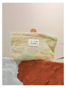 Knitted fuzzy cosmetic pouch with colorful letter label detail, soft texture and chic design.