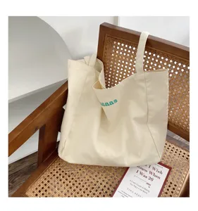 Detail view of cream canvas tote bag on rattan chair, showing fabric texture and casual style.