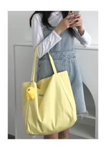 Cream large canvas tote bag detail view, casual single shoulder bag with cute plush pendant.
