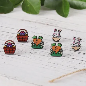 Detailaufnahme des Oster-Ohrring-Details mit niedlichem Hasen und Karotten auf Holztisch.