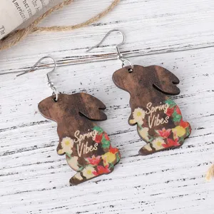 Detailed shot of wooden rabbit earrings with floral print and spring vibes text for Easter.