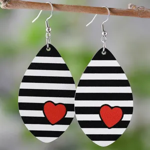 Primo piano di orecchini in legno a goccia con strisce bianco-nero e cuore rosso.