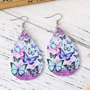 Detailaufnahme der tropfenförmigen PU-Leder-Ohrringe mit blauen Schmetterlings- und Glitzermotiven.