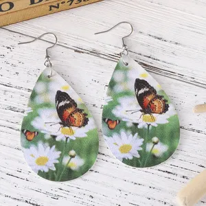 Nahaufnahme Detail der tropfenförmigen PU Leder Ohrringe mit Schmetterling und Gänseblümchen.