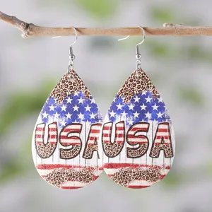 Detailed shot of American flag leopard print teardrop PU leather earrings hanging on branch.