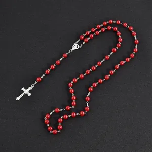 Red bead rosary necklace detail view, showcasing silver cross pendant and vibrant red pearls.