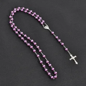 Detailed view of the purple imitation pearl rosary necklace with silver cross and medal.