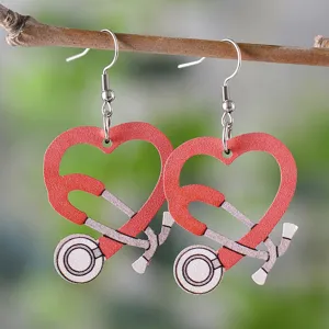Gros plan des boucles d'oreilles stéthoscope cœur en bois rouge, bijoux infirmière.
