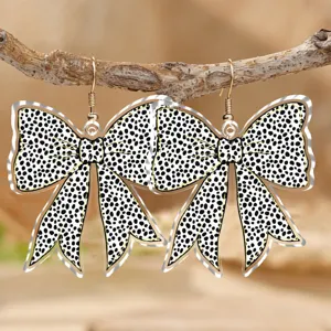 Primo piano dettagliato degli orecchini pendenti in acrilico con fiocco animalier su un ramo.