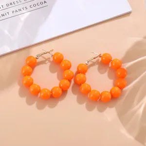 Pendientes de aro con cuentas naranja estilo caramelo joya llamativa de moda actual.