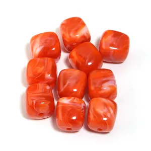 Primer plano detallado de cuentas cuadradas de acrilico marmolado naranja para joyeria.