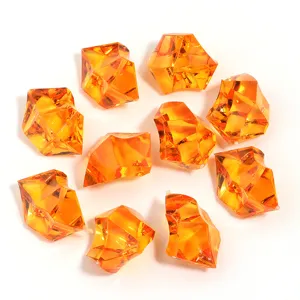 Close-up detail of orange acrylic crystal stones, irregular transparent ice cube decor.