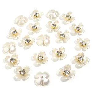 Close up of white resin imitation pearl flower charms with sparkling rhinestones for DIY crafts.