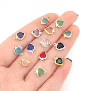 Detailed view of colorful crystal heart pendant charms with gold and steel rims for DIY jewelry.