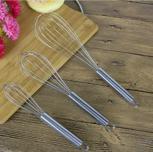 Close-up detail view of three different sizes of manual stainless steel wire whisks for kitchen baking.