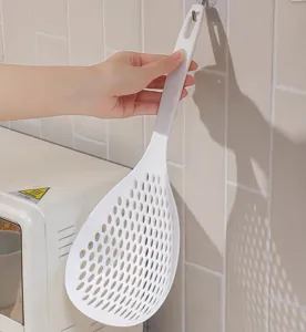 Vue détaillée de l'écumoire de cuisine en nylon blanc avec trous de drainage et long manche.
