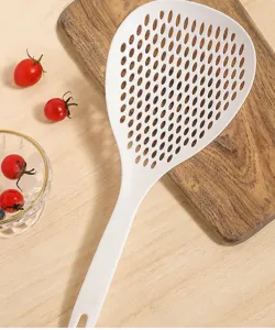 Détail de grande écumoire de cuisine en nylon blanc, montrant des trous de drainage denses.
