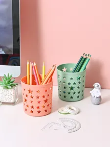 Vista detallada de portalápices de plástico con estrellas en rosa y verde sobre un escritorio limpio.
