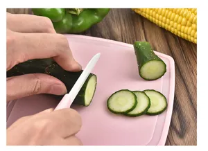 Ceramic fruit knife set with pink cutting board, sharp blade slicing fresh cucumber easily.