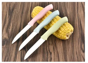 Close-up detail view of ceramic fruit knife set with colorful handles displayed on corn.