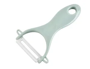 Close-up detail of a kitchen ceramic fruit peeler with ergonomic green handle and white blade.