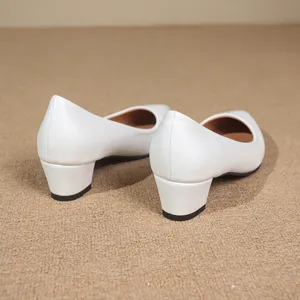 Detailed view of white pointed toe block heel pumps showing texture and heel design.